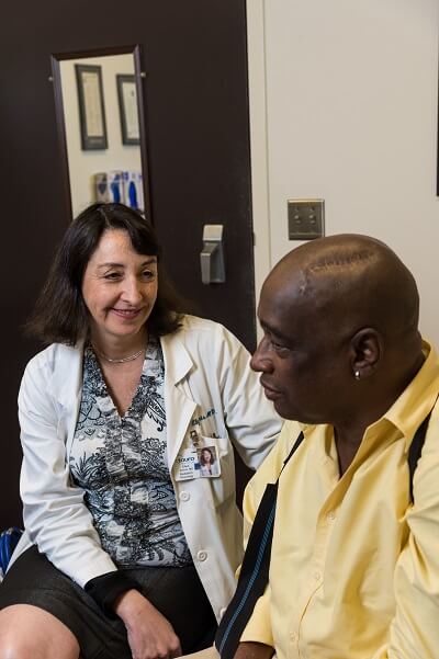 Smiling female physician sitting with middle aged male patient